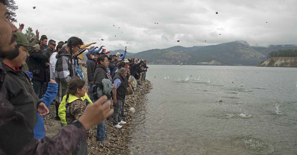 Participants in a salmon ceremony at the historic site of Kettle Falls throw rocks into the water to mimic the sounds heard underwater by returning salmon.