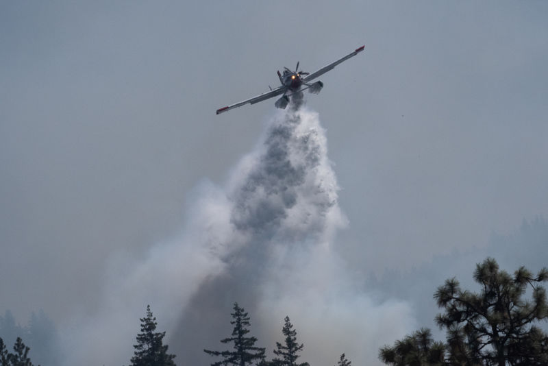 Fireboss plane dumps 800 gallons of water on hot spot next to Dry Creek Road. Fireboss flys on Columbia River surface scooping up water into it’s holding tanks.