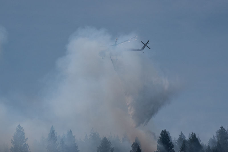 Large helicopter dumps water from its tank on hot spot. Pilots skilled at flying in dense smoke.